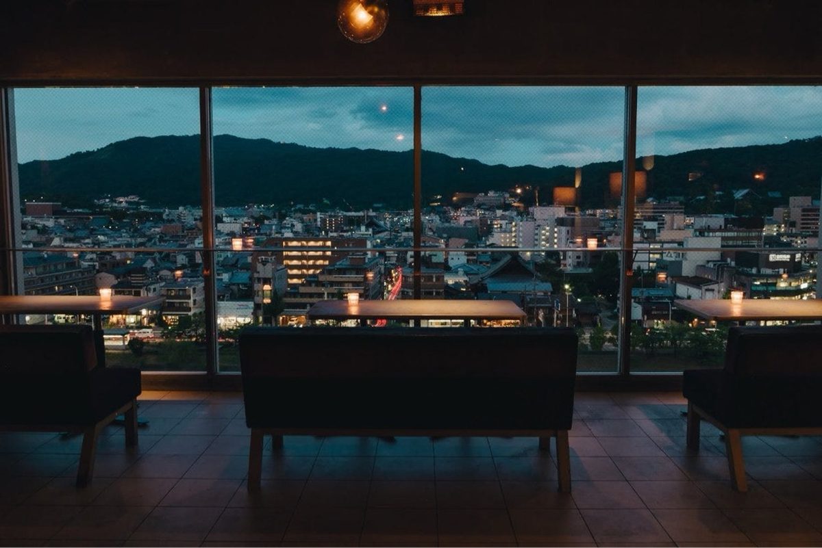 View over Kyoto at dusk from a rooftop bar with the Higashiyama mountains in the background